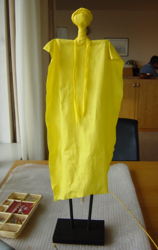 AFRIKAANSE VROUW van papier Het lichaam is met papier bekleed en bewerkt met behangsellijm. Daarna alles geel geverfd en klaar voor afwerken