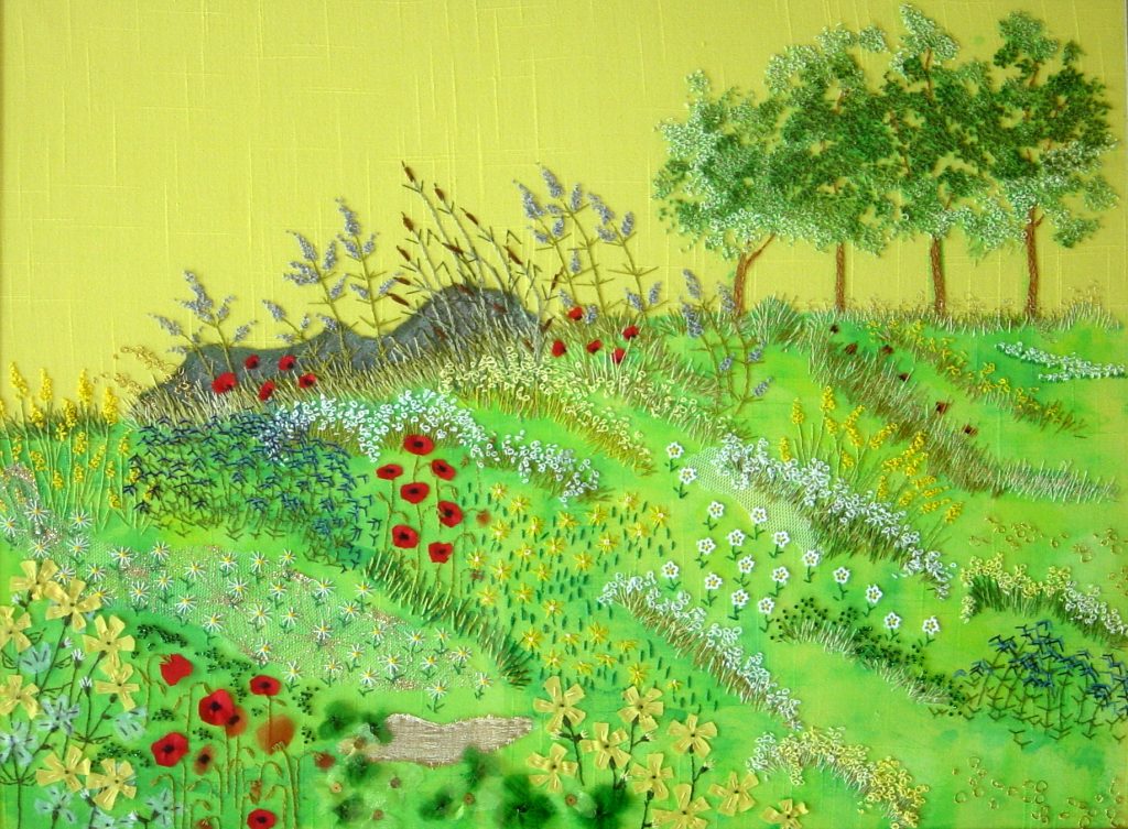 BLOEMEN IN DE BERM Freestyle. Ondergrond geel katoen met daarop textielverf, borduurgaren, lapjes, kraaltjes en naaigaren. Ontwerp: Het ontwerp is dezelfde als wandkleed 5 VELDBLOEMEN; een idee opgedaan uit een boek. Maar er is andere stof met een andere kleur gebruikt.
