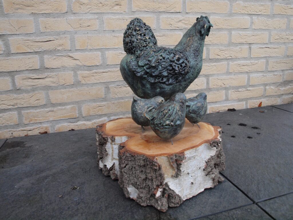 Kip met kuikens, witte klei grove chamotte, gestookt op 1040° C. Bewerkt met verf.